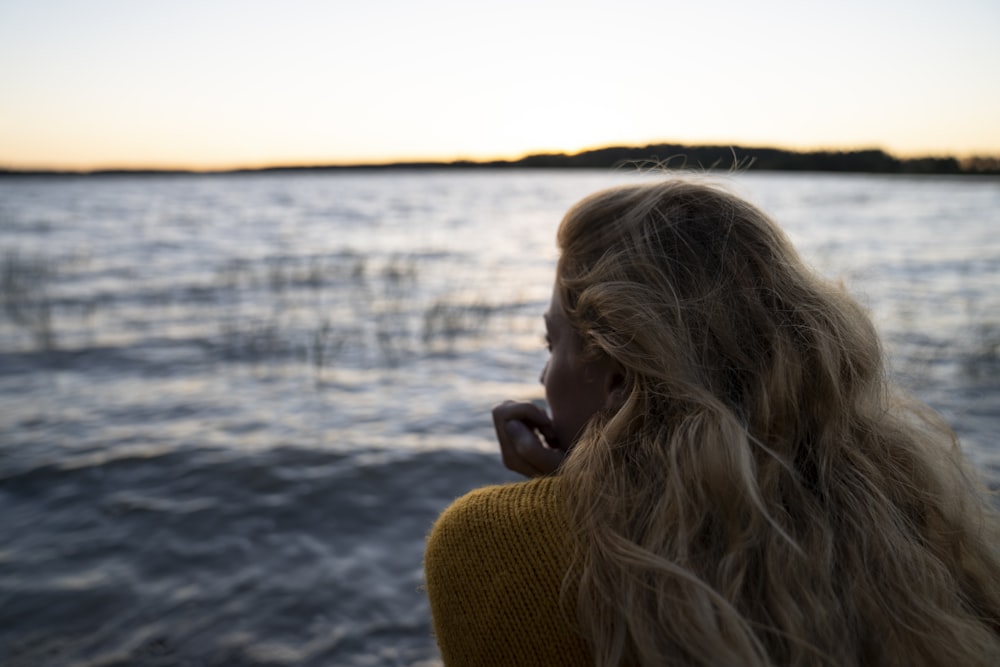 Une femme aux longs cheveux blonds regardant l’eau