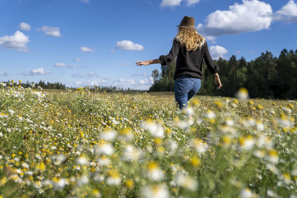 a woman walking through a field of wildflowers