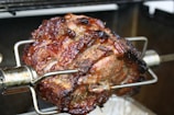 Close-up of a golden, crispy rotisserie chicken turning slowly over glowing coals.