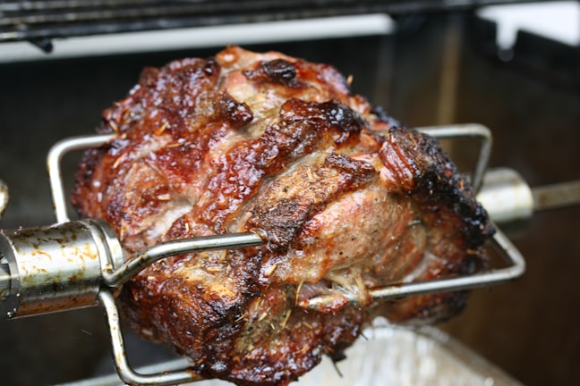 Close-up of a wood-fired rotisserie with golden roasted chicken turning slowly.