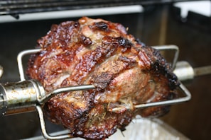 Close-up of a golden, crispy rotisserie chicken turning slowly over glowing coals.