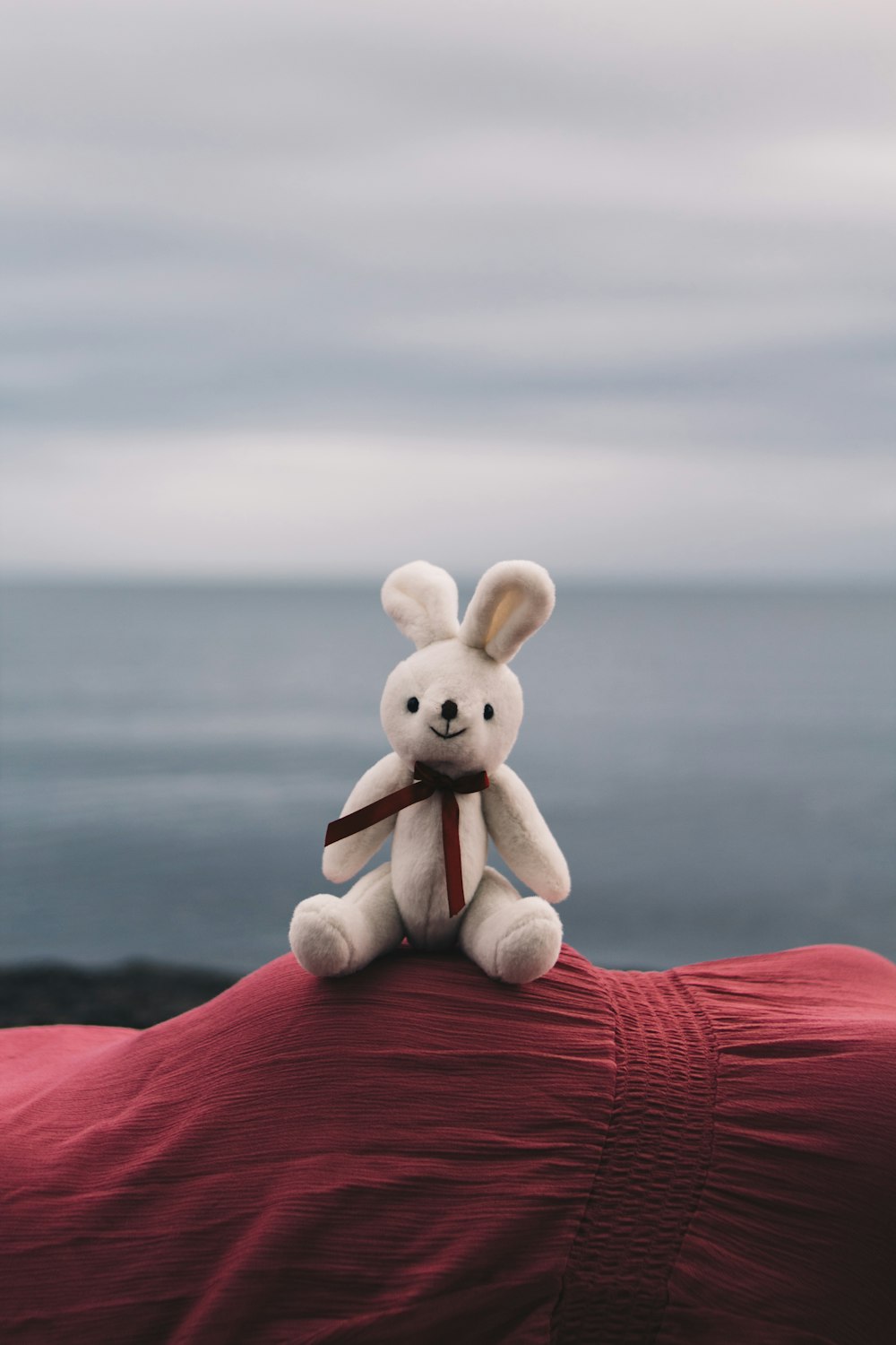 a white stuffed rabbit sitting on top of a red blanket