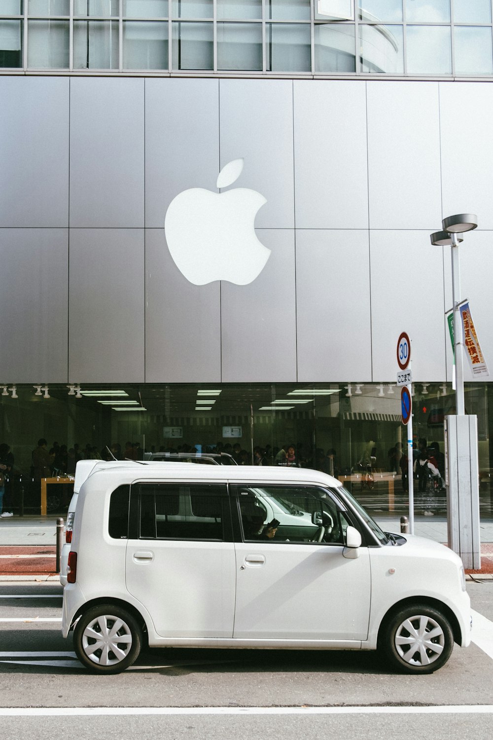 Ein weißer Mini-Van parkt vor einem Apple Store