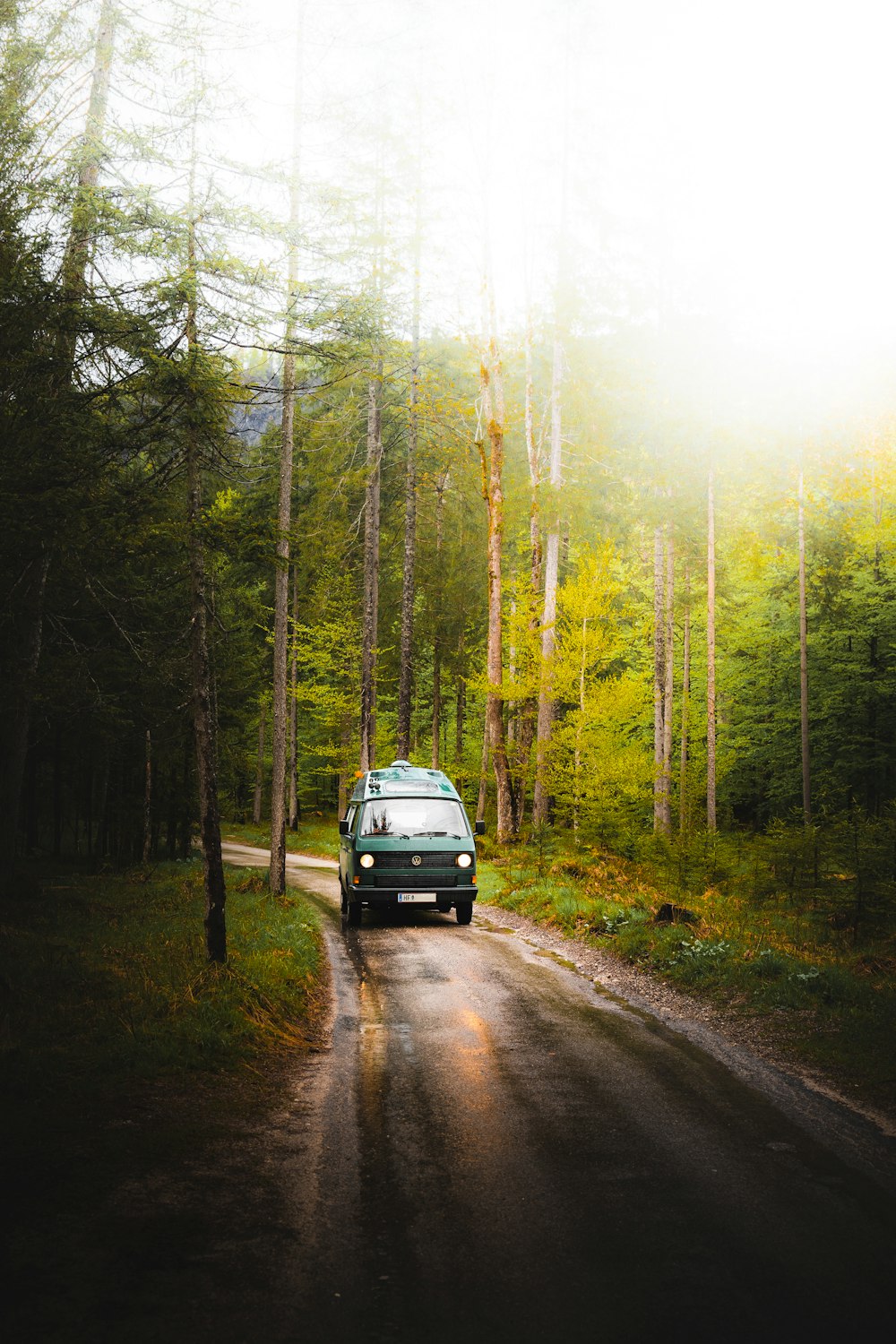 a van driving down a dirt road in the woods