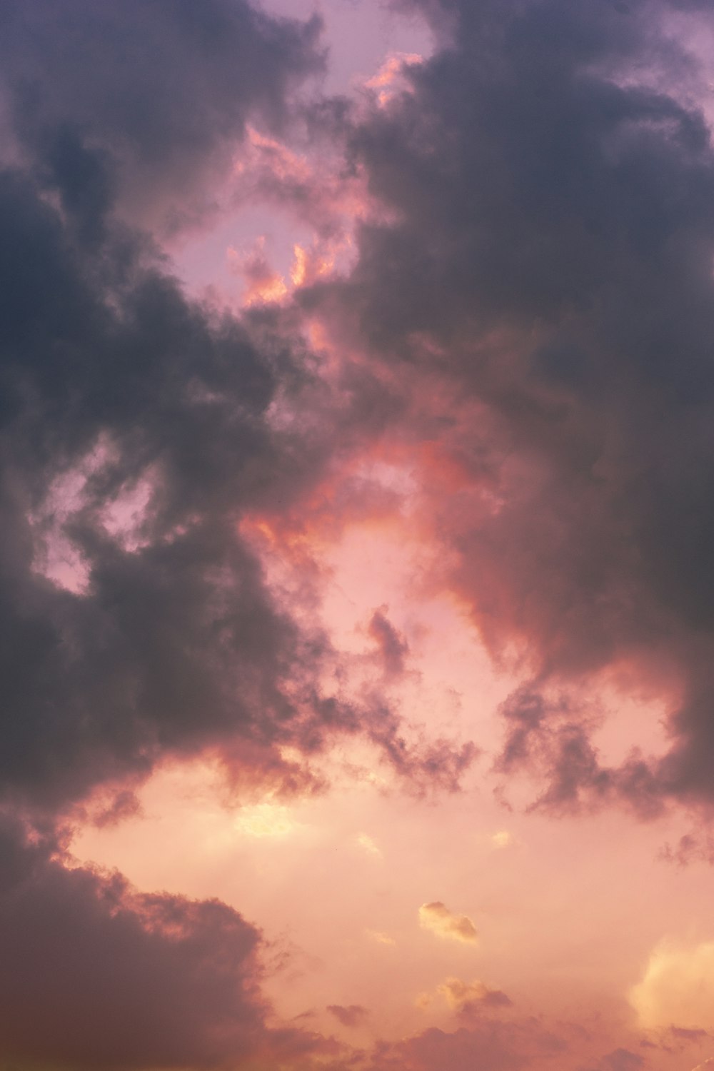 a plane flying through a cloudy sky at sunset