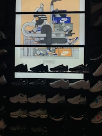 The image features a display of various Nike sneakers arranged on shelves. Above the sneakers is a vibrant, illustrated backdrop with expressive characters and Nike shoe boxes. The illustration depicts abstract figures and objects, incorporating geometric shapes and lines with a few cartoonish bird characters.