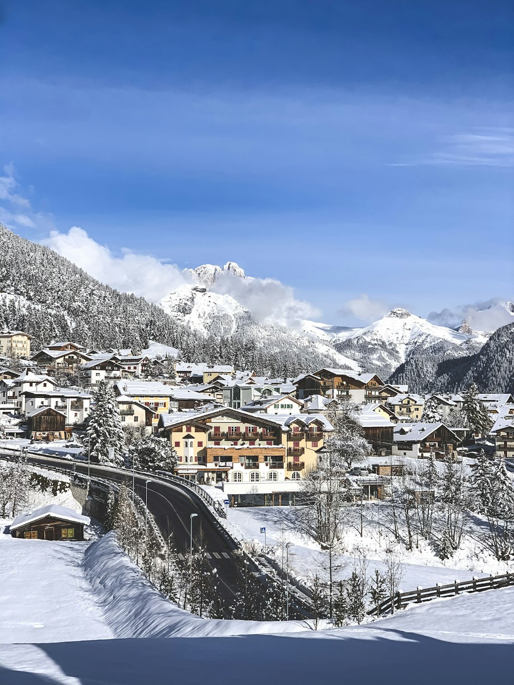 a snow covered mountain town with a bridge in the foreground