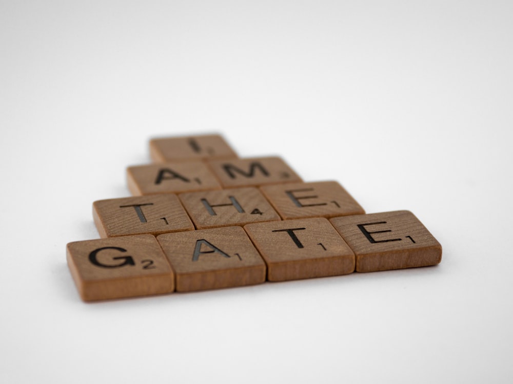 a wooden scrabble with the words i am the gate on it