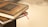 Two books with dark, intricately designed covers and golden embossed text are stacked, with a red ribbon bookmark peeking out.