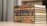 A stack of ornately decorated hardcover books with embossed Arabic script on the spines, arranged neatly on a light-colored table. The background is softly blurred, creating a focus on the books.