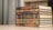 A stack of ornately decorated hardcover books with embossed Arabic script on the spines, arranged neatly on a light-colored table. The background is softly blurred, creating a focus on the books.