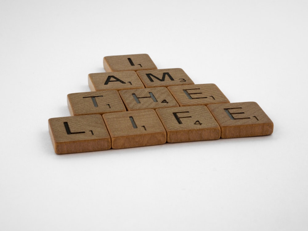 scrabble tiles spelling i am the life on a white background