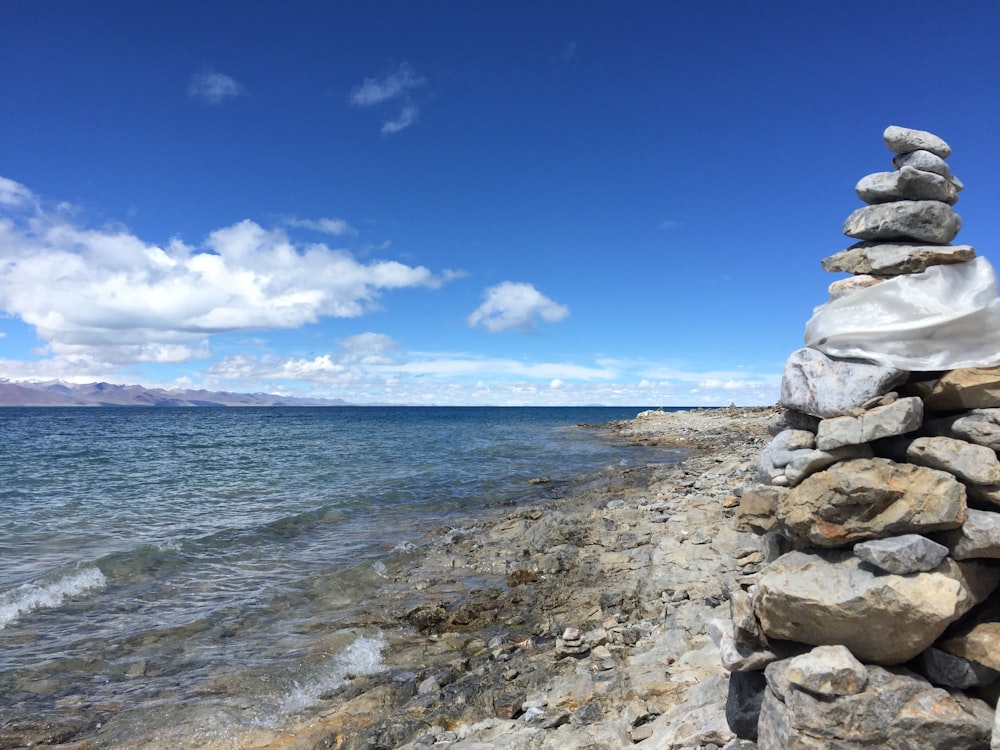 a pile of rocks sitting on top of a beach next to the ocean