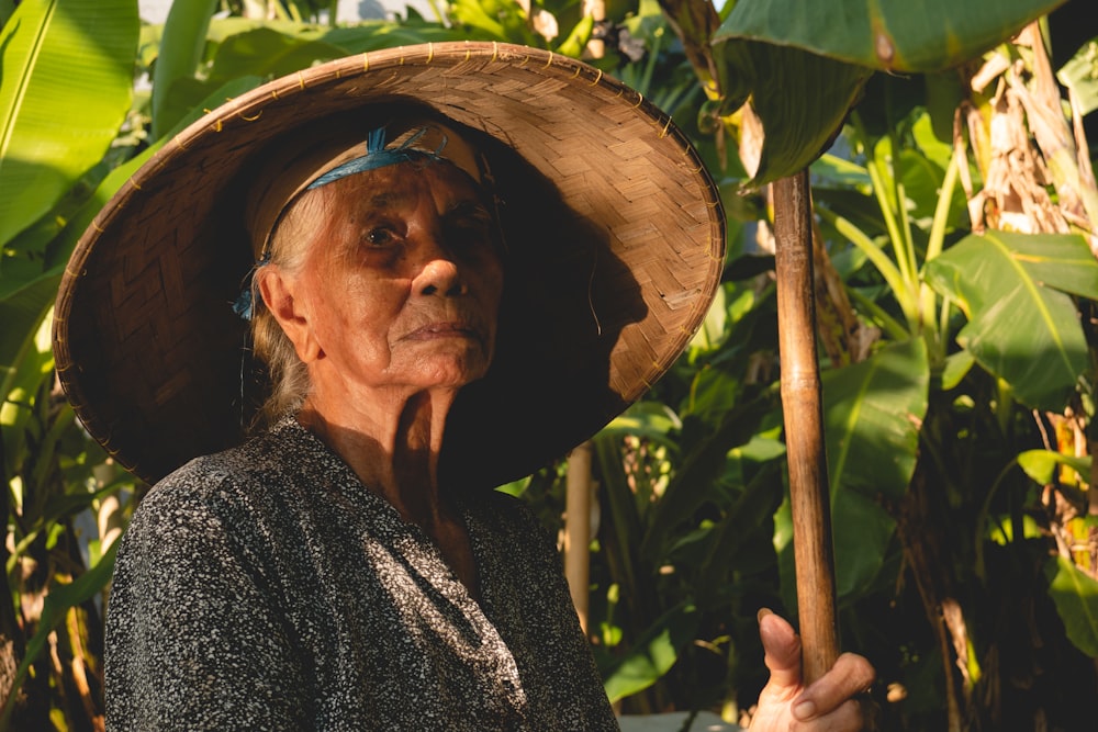 an old woman wearing a straw hat and holding a stick