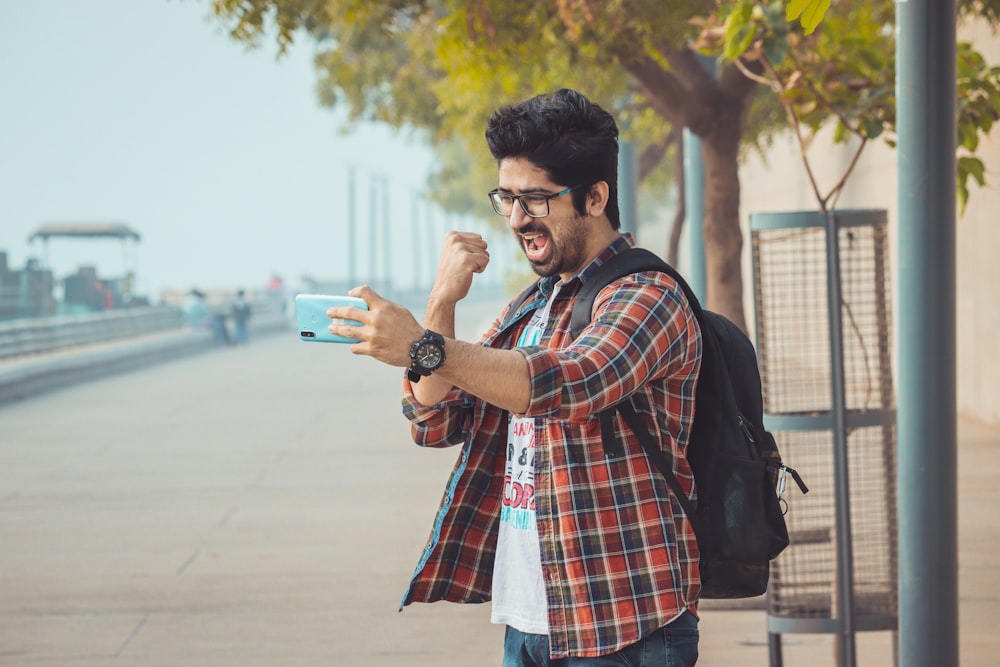 um homem com uma mochila tirando uma foto com seu celular