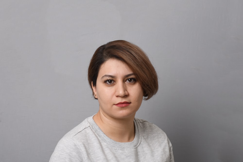 a woman in a gray shirt is posing for a picture