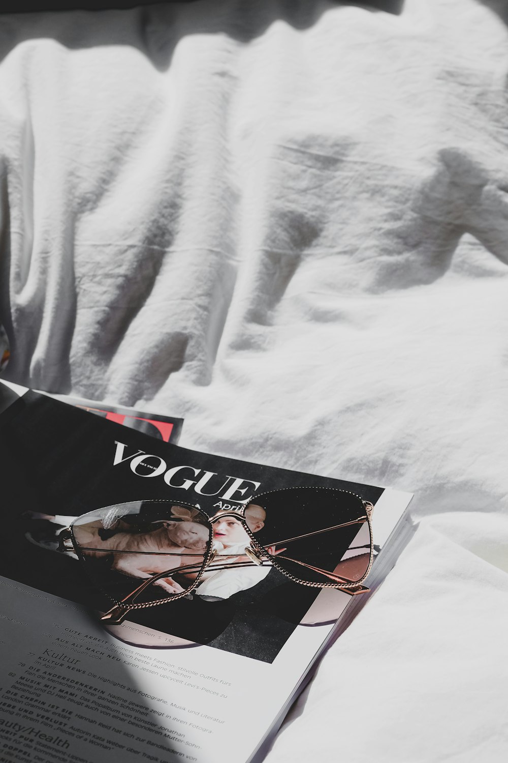 una rivista posata sopra un letto accanto a un cuscino