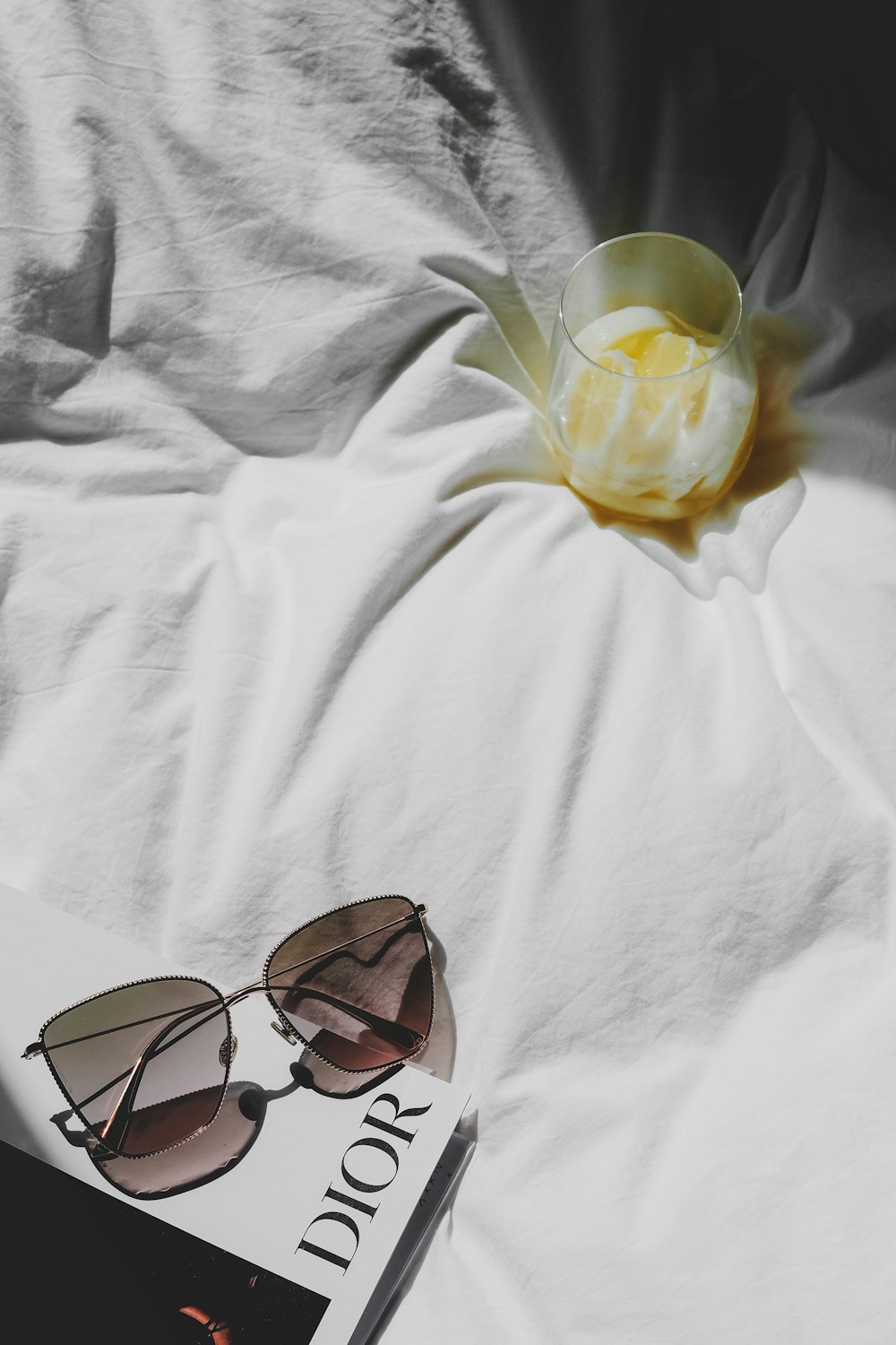 Un libro y gafas de sol en una cama con una flor