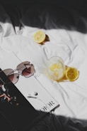 a book with sunglasses and lemons on a bed