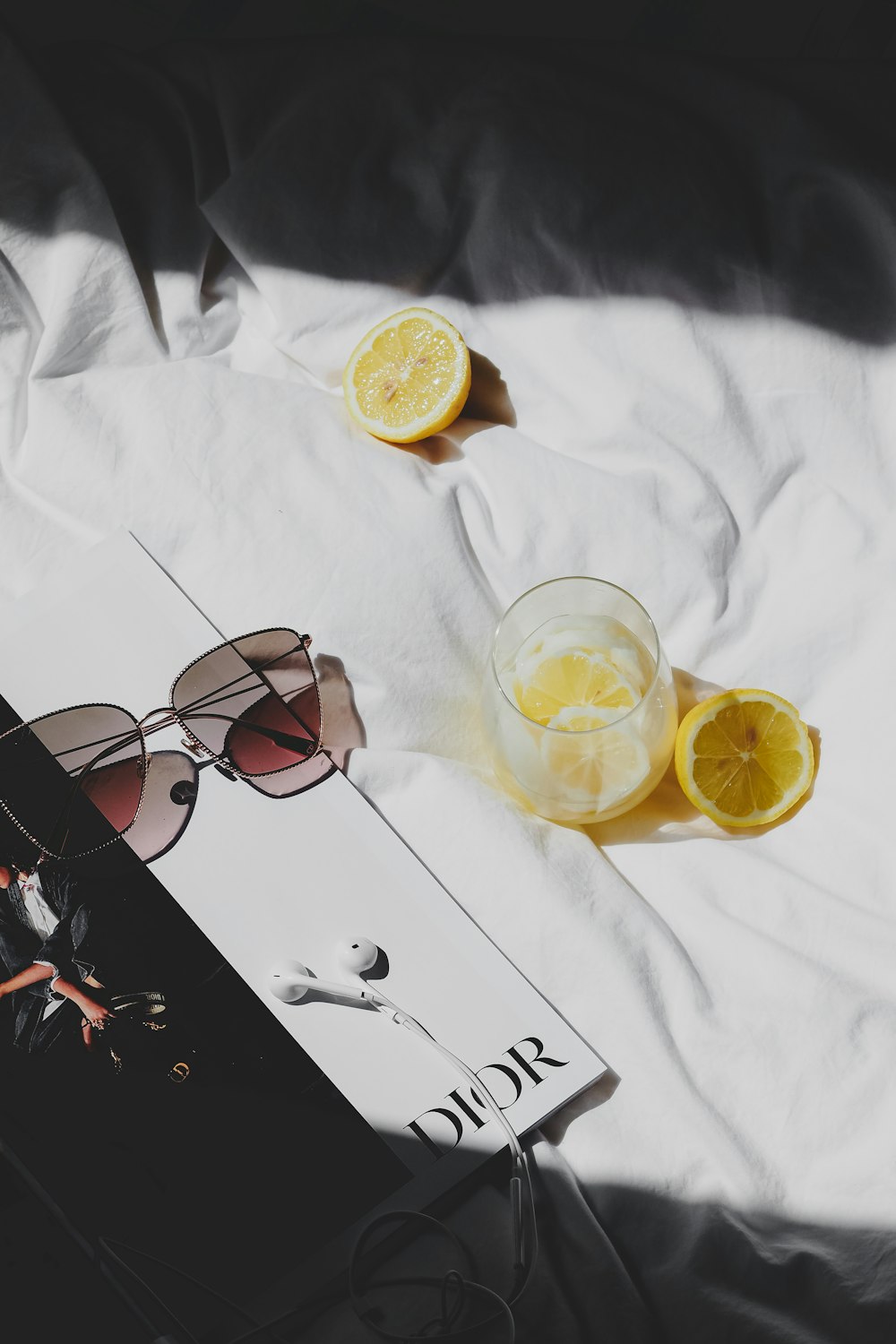a book with sunglasses and lemons on a bed