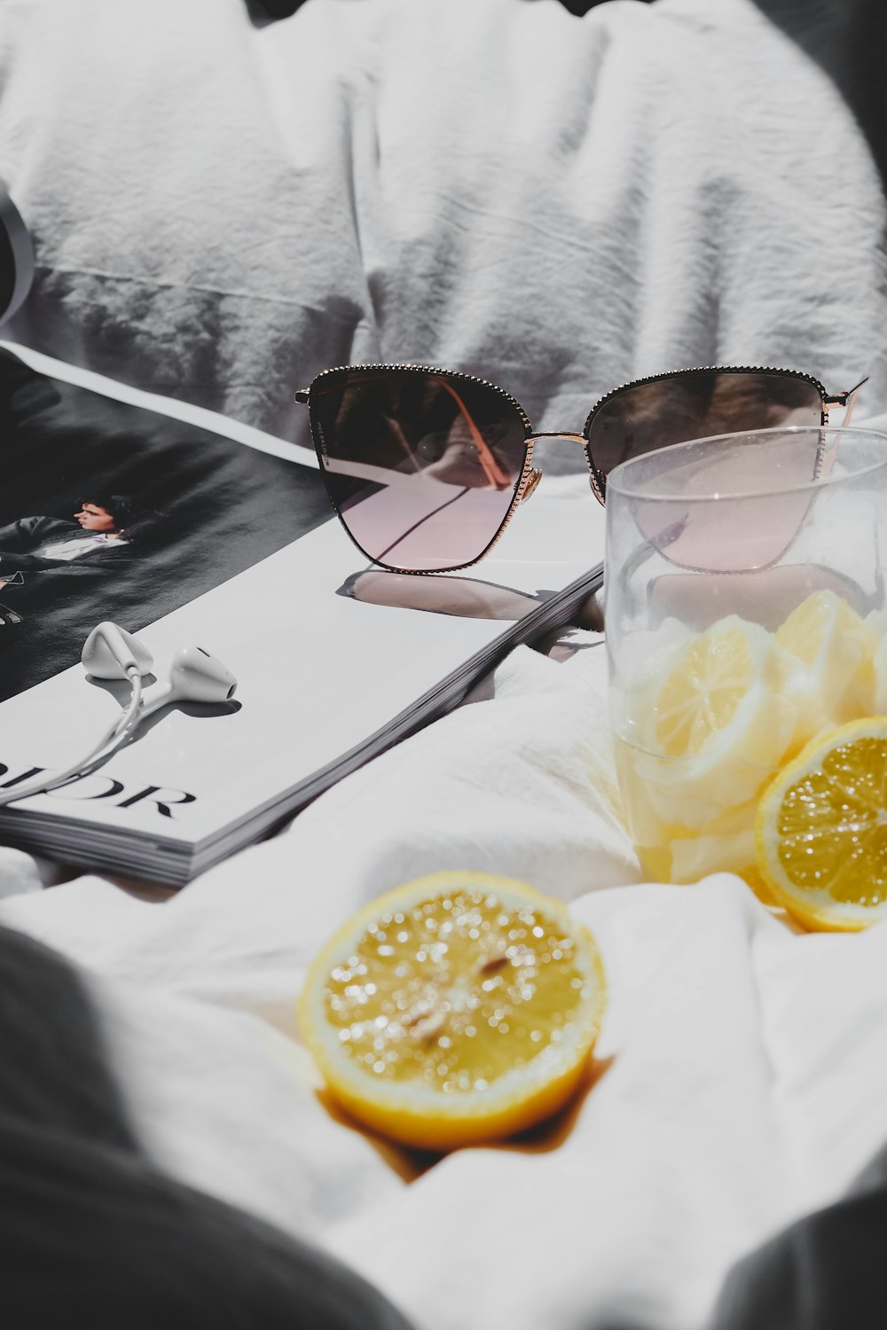 a pair of sunglasses sitting on top of a bed next to a sliced lemon