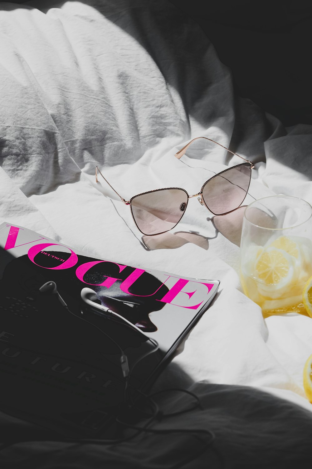 a pair of sunglasses sitting on top of a bed next to a book