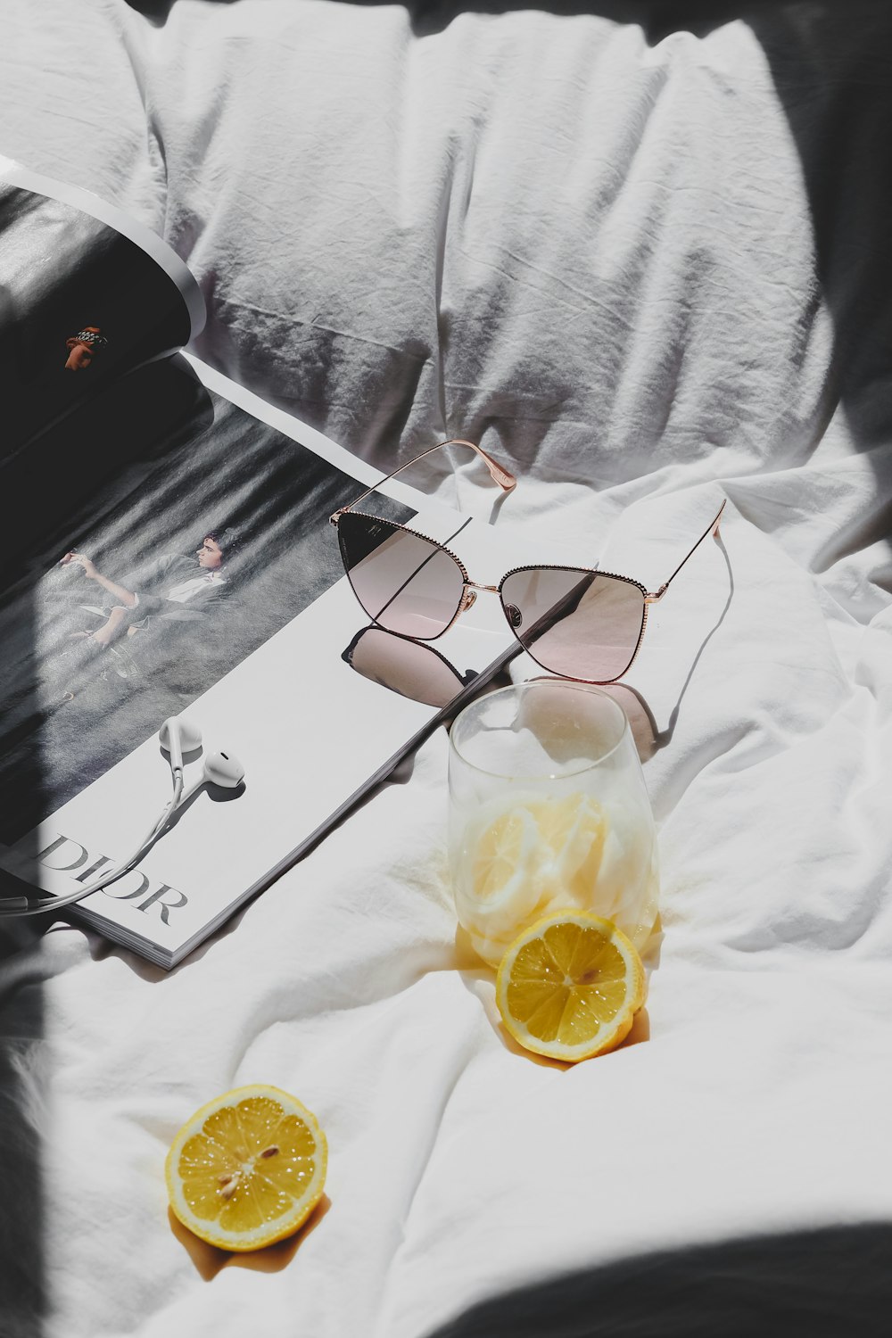 a pair of sunglasses sitting on top of a bed next to an orange slice