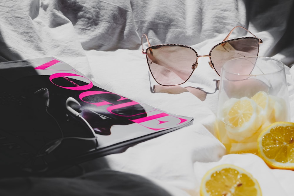 a pair of sunglasses sitting on top of a bed next to a book