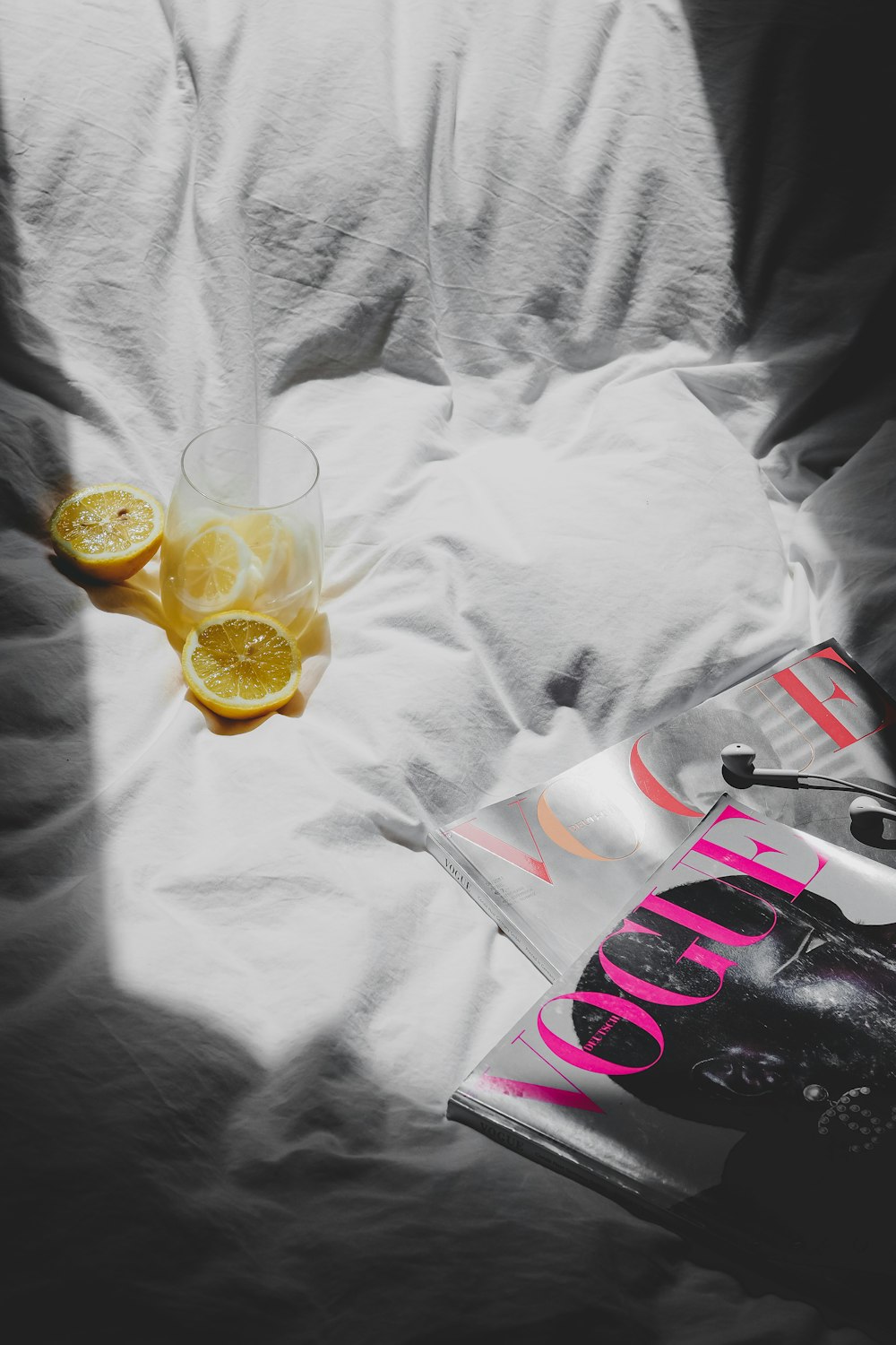 a glass of orange juice and a book on a bed