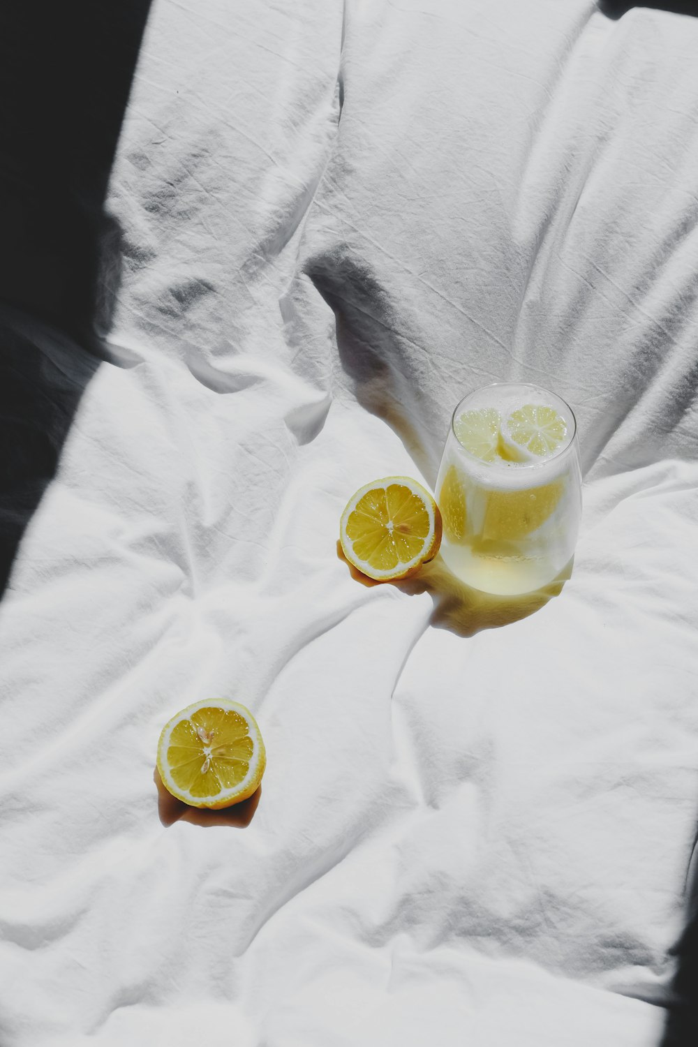 a glass of lemon juice sitting on top of a bed