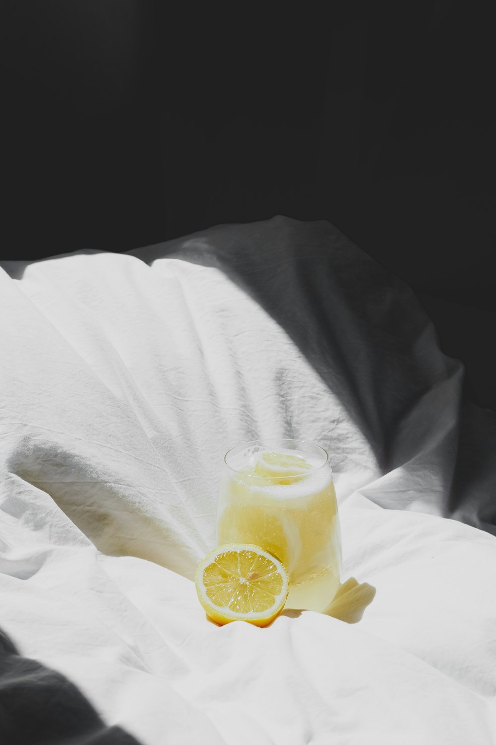 a glass of lemon juice sitting on a bed