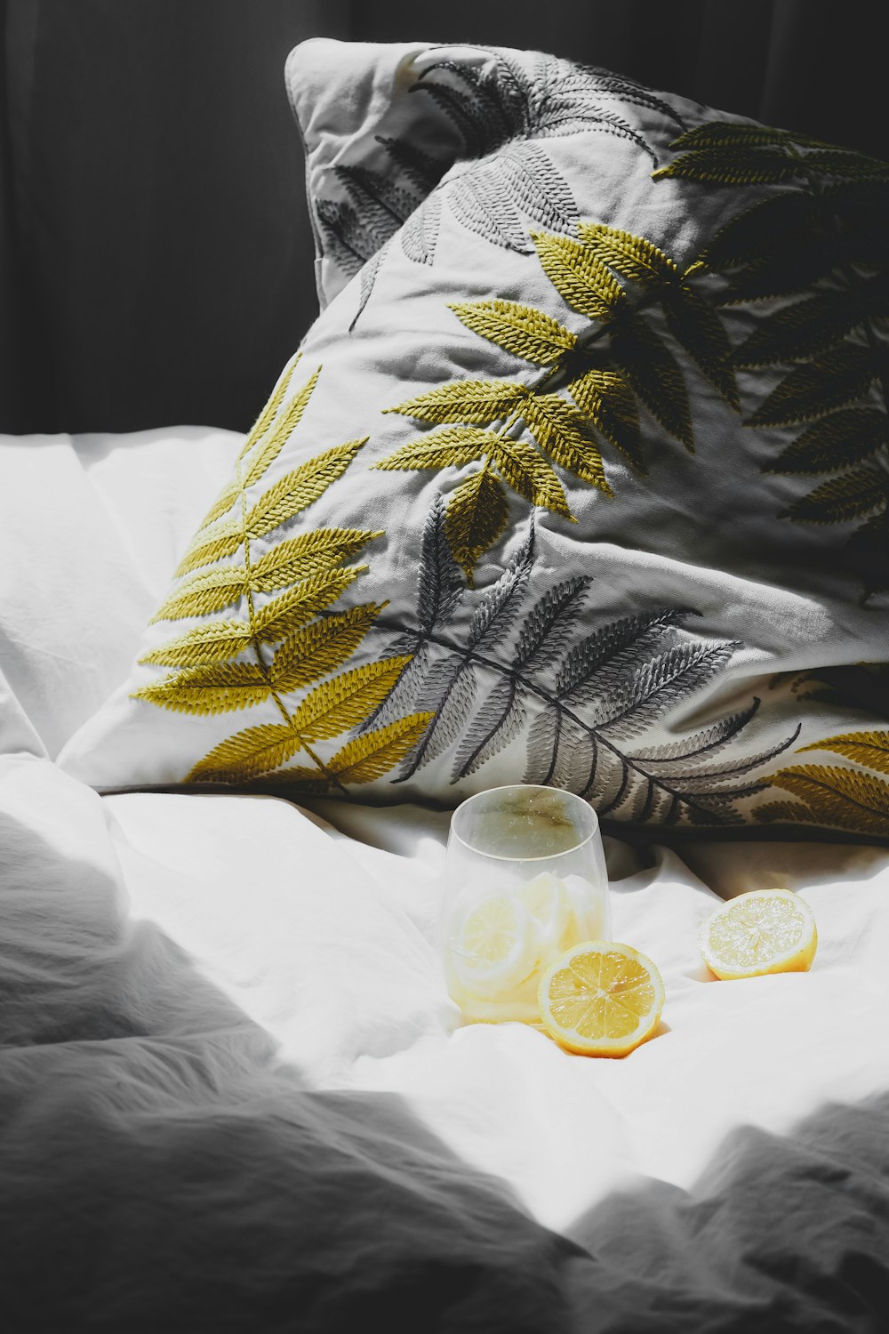 a bed topped with pillows and a cup filled with lemons