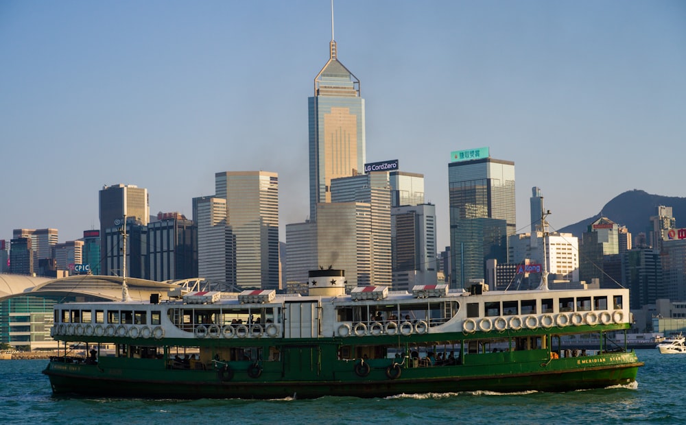 a green and white boat in front of a city skyline