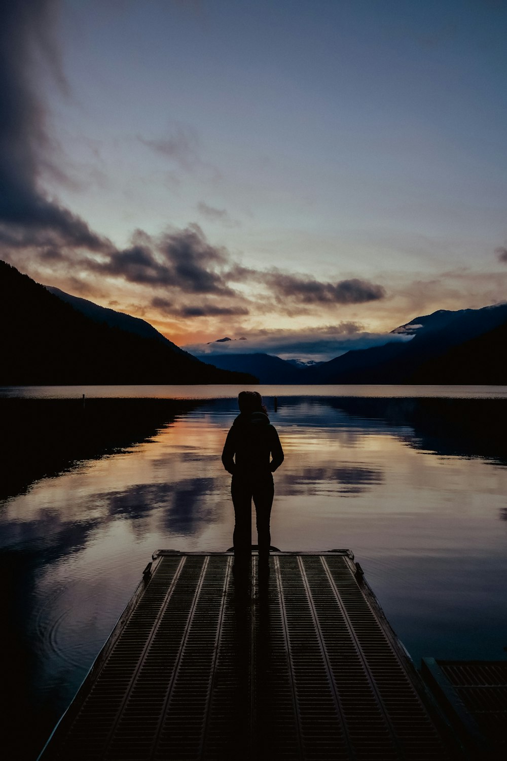 a person standing on a dock in front of a body of water