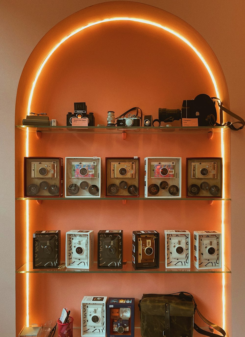 a room with a shelf filled with old cameras