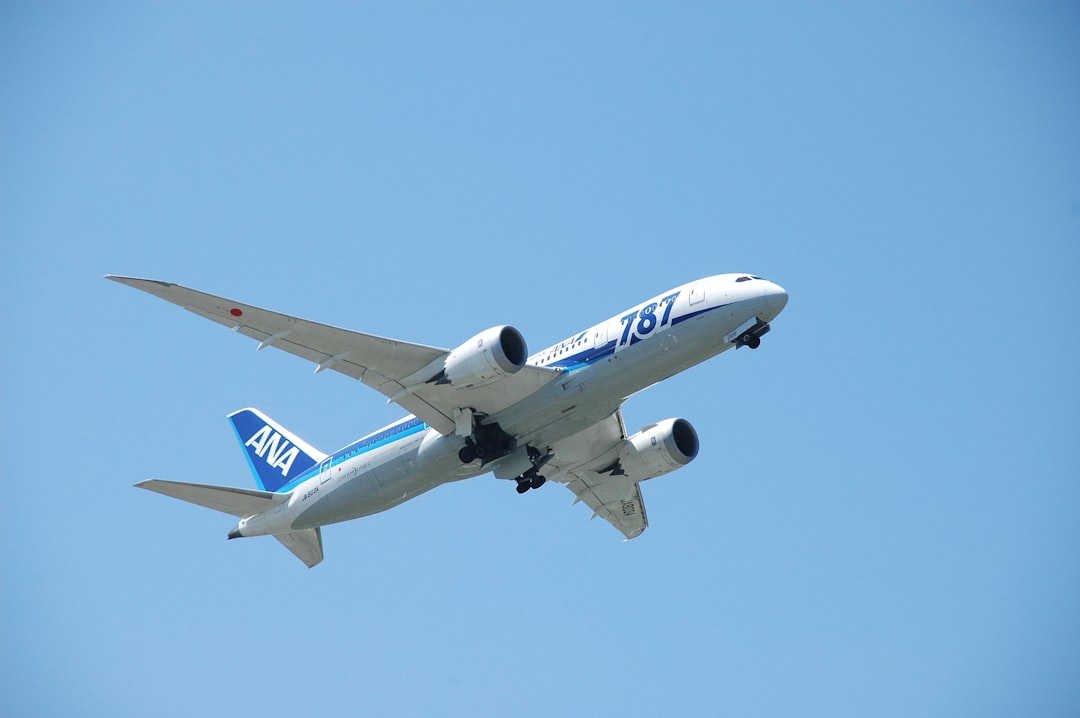 a large jetliner flying through a blue sky, Nippon airways took off from TSA airport. Beoing 787-800