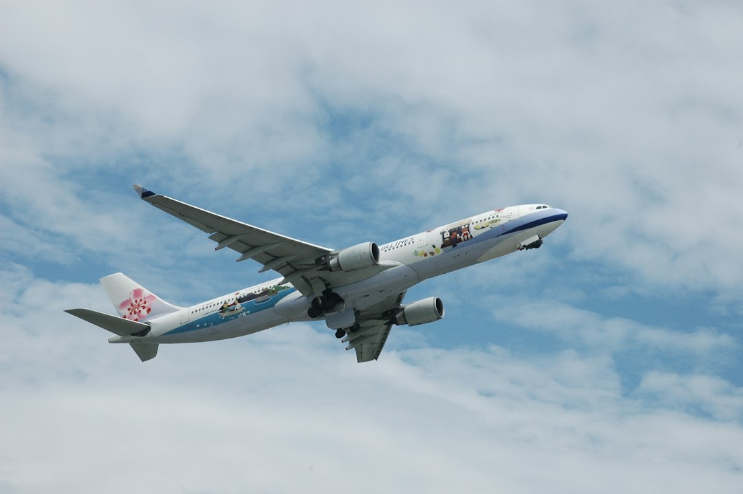 a large passenger jet flying through a cloudy blue sky, The exterior painting of the aircraft doesn
