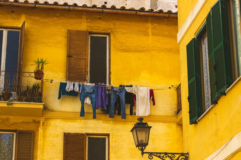 clothes hanging out to dry on a clothes line in front of a yellow building