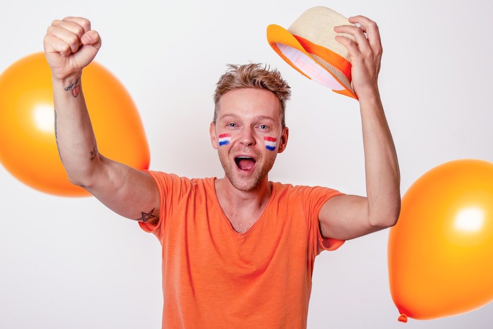 Un hombre sostiene globos y un sombrero