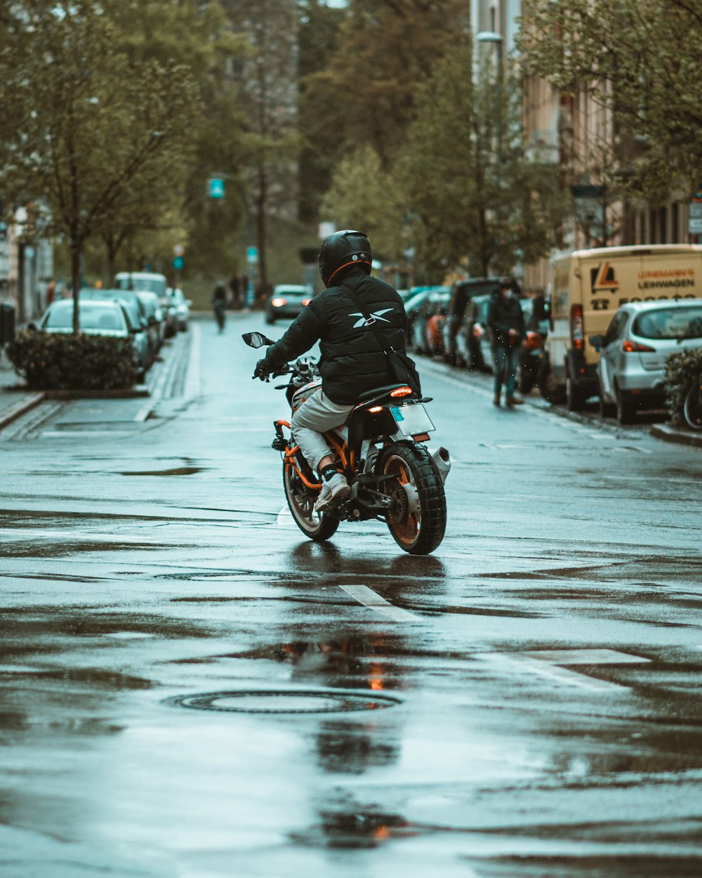 a man riding a motorcycle down a rain soaked street