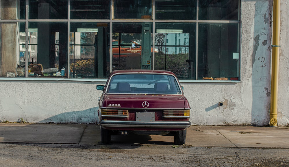 red car parked beside building during daytime