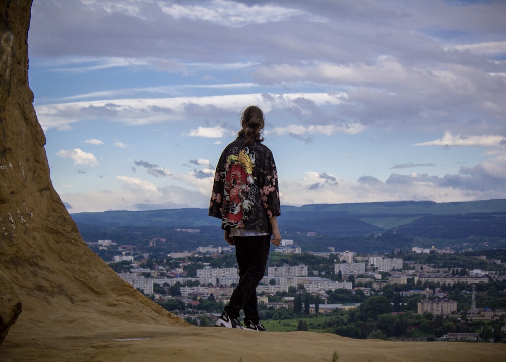 uma pessoa em pé no topo de uma colina com vista para uma cidade