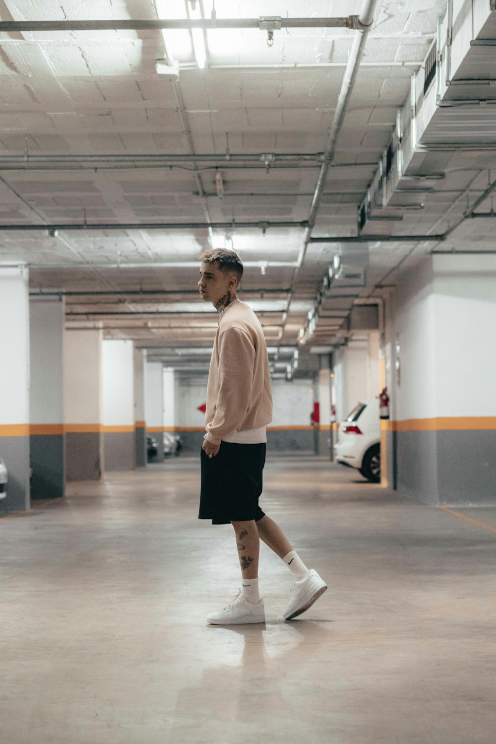 a man walking in a parking garage with a car in the background