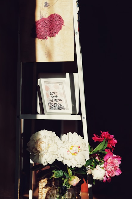 a ladder with a vase of flowers on top of it