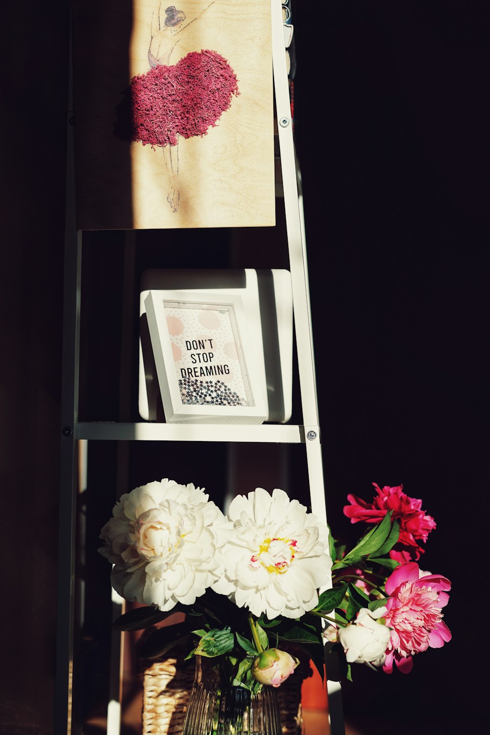 a ladder with a vase of flowers on top of it