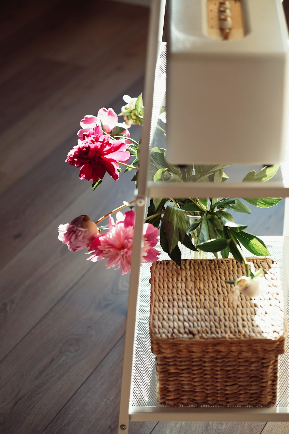 a white shelf with a basket and flowers on top of it