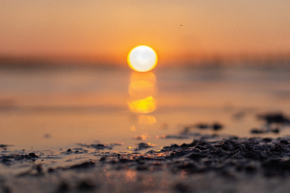 the sun is setting over the water on the beach