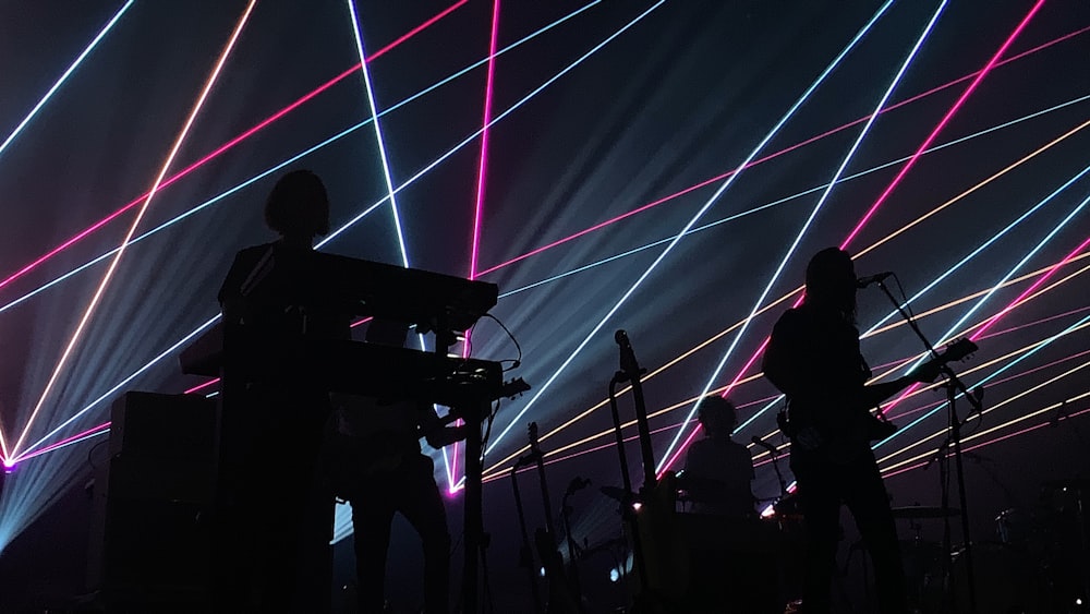 uma banda tocando no palco com luzes laser ao fundo