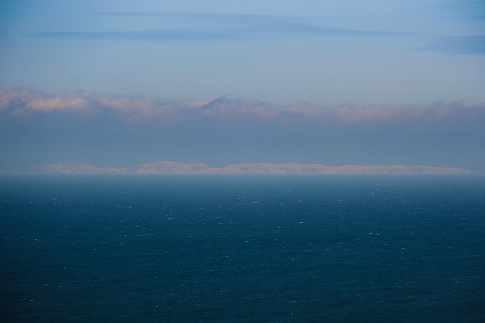 a large body of water with a mountain in the distance