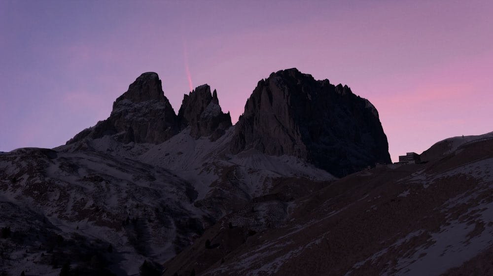 Eine Gruppe von Bergen mit einem rosa Himmel im Hintergrund